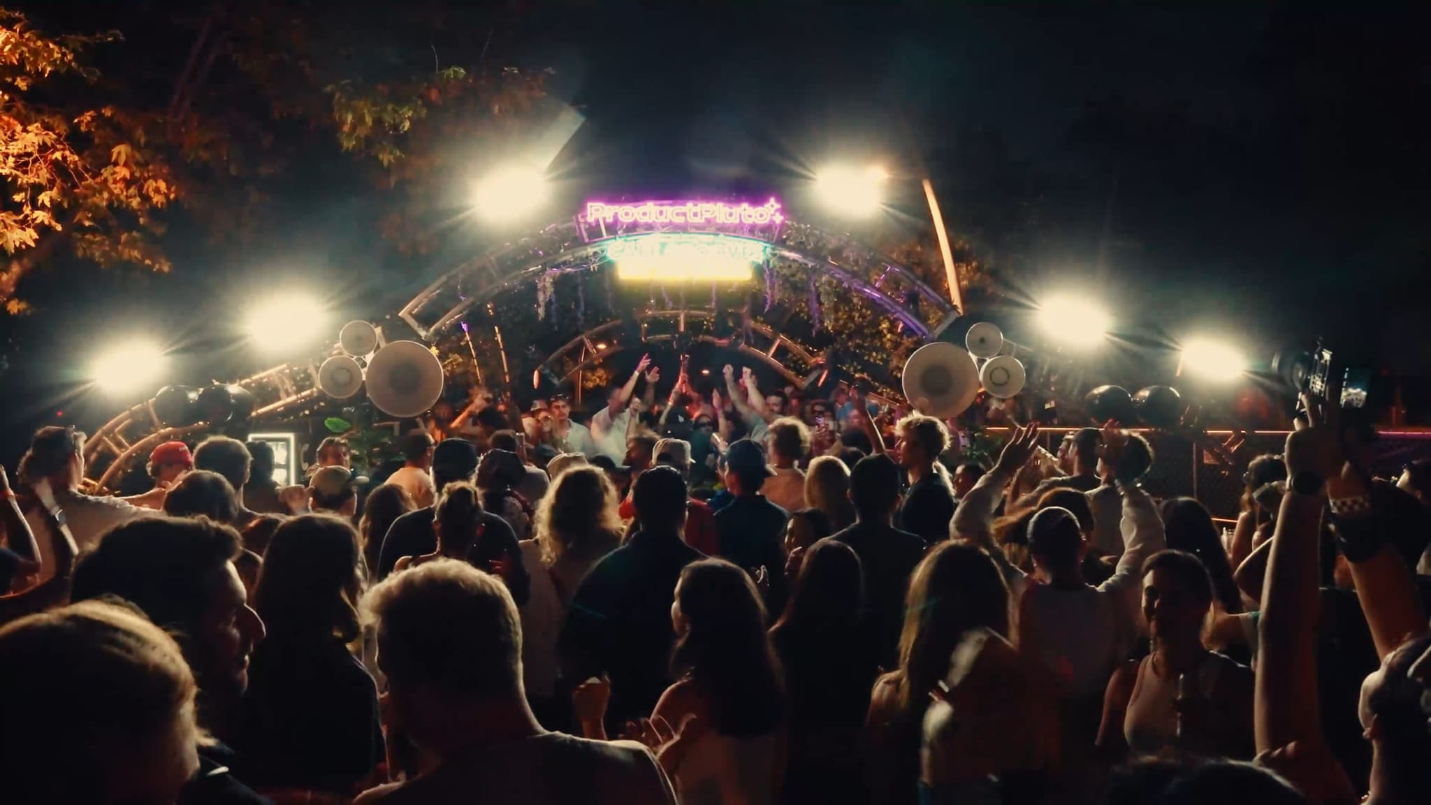Wide shot of the crowd facing the arch as the stage lights flare