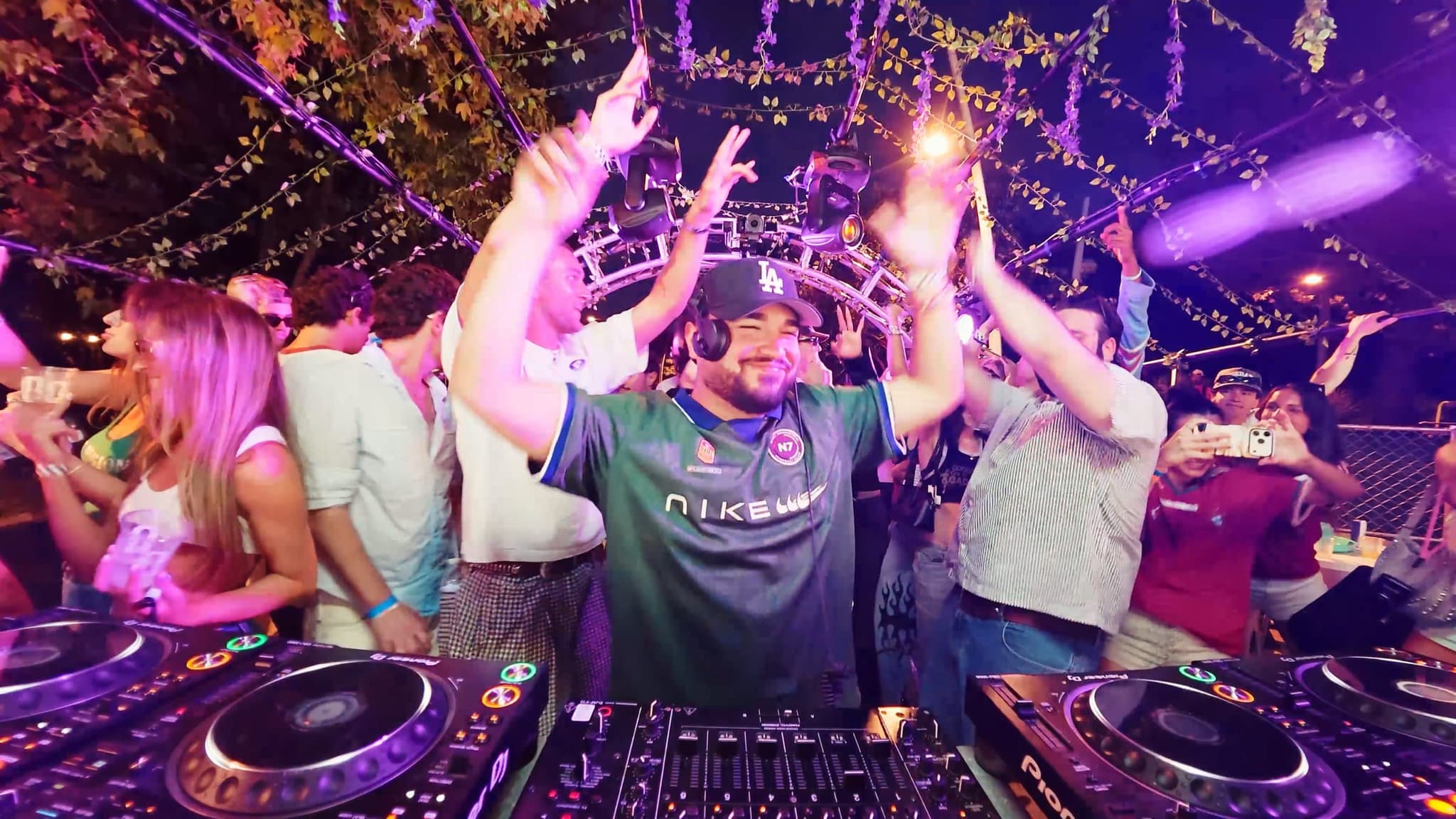 The DJ throwing both hands up to the crowd from the booth