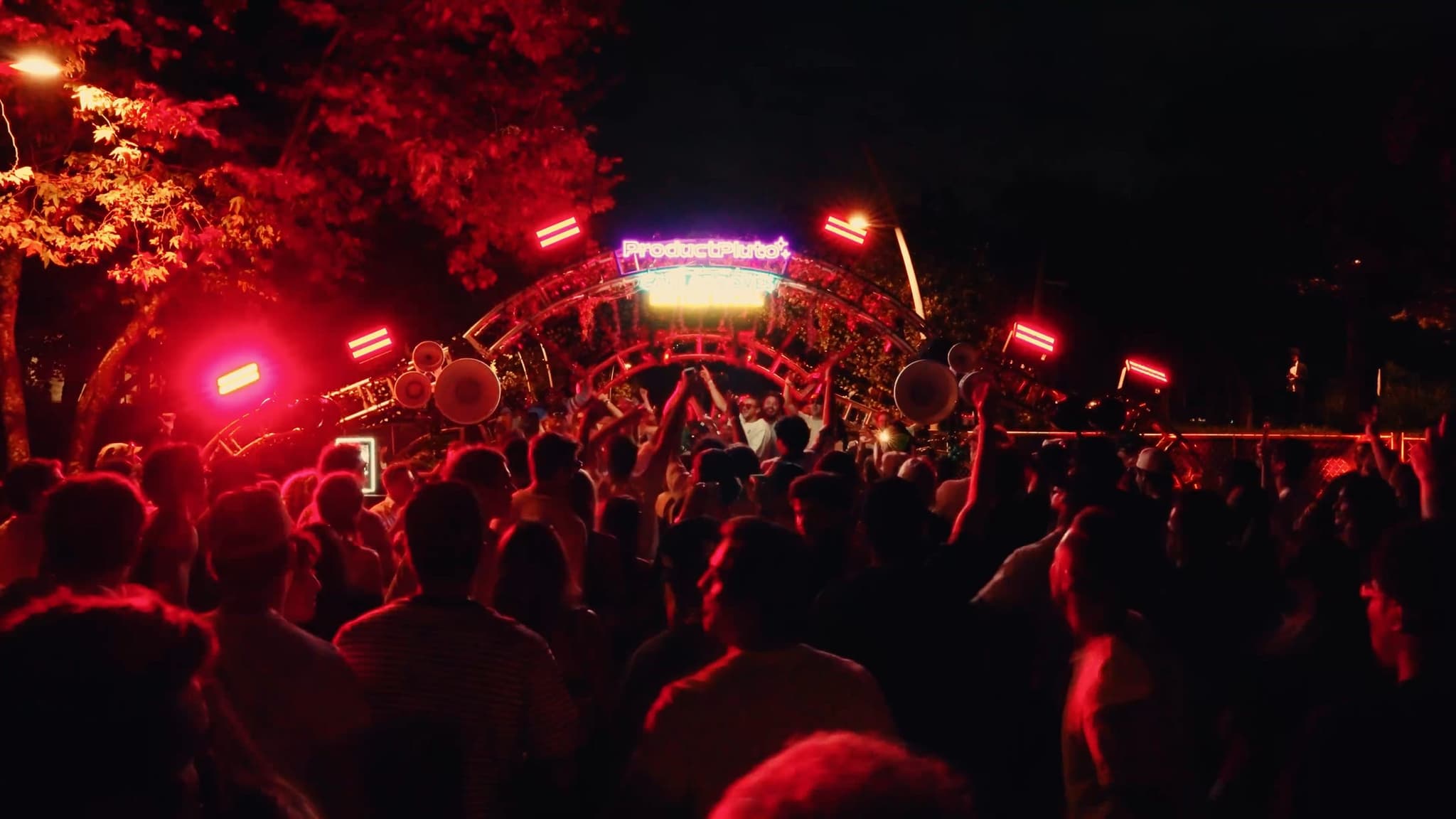 A dense crowd dancing in front of bright white stage lights
