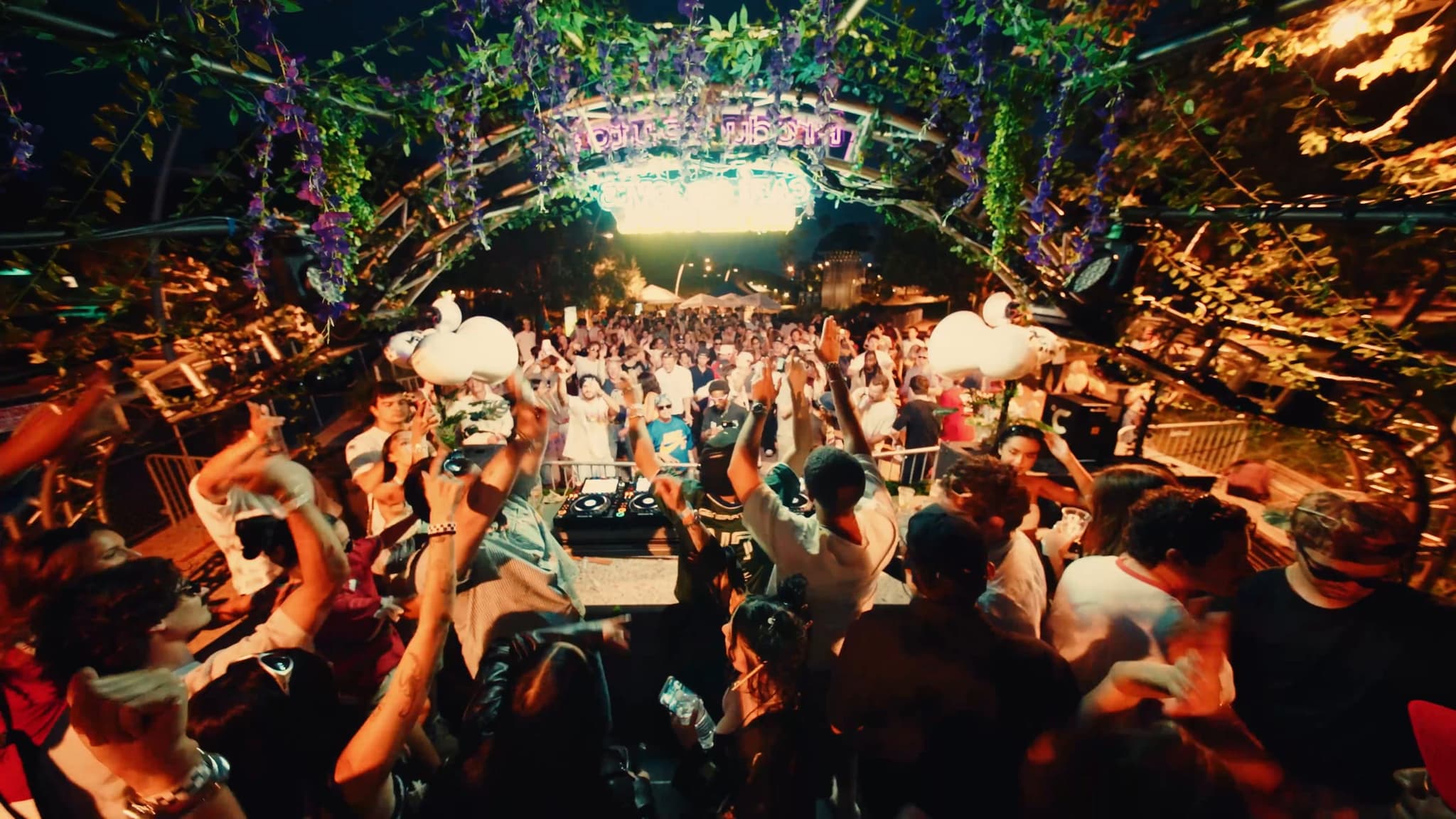 Hands up across the dance floor under the arch, lit purple and gold